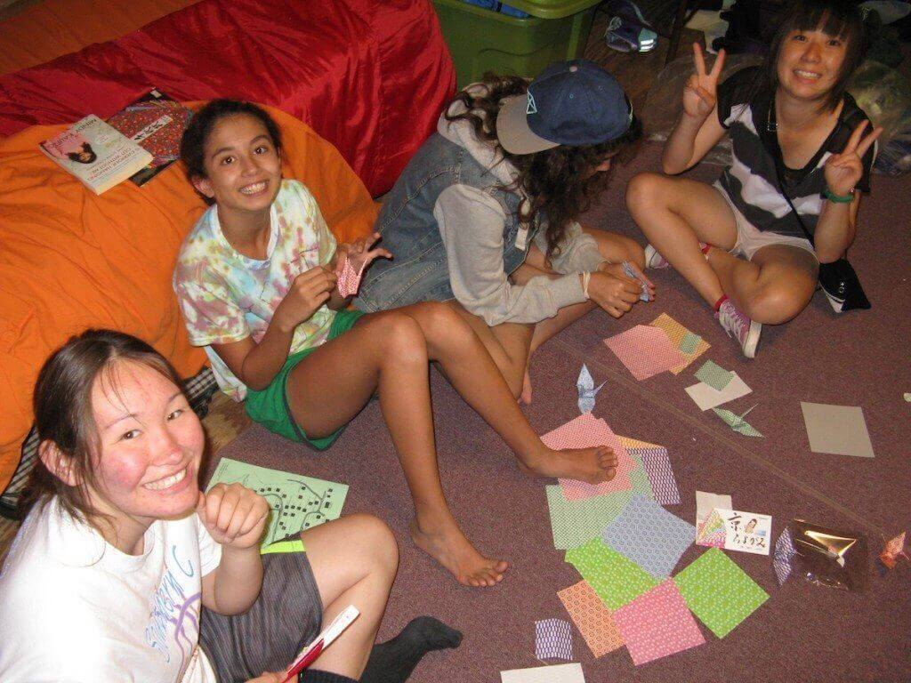 Tomoha, from Japan (right) teach her cabin mates how to make origami paper cranes. From left - Naomi, from Crow Nation; Devi, from Maryland, Maryland; Saja, from Libya; Tomoha, from Japan